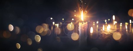 Téléchargez les photos : Flammes de bougies dans l'obscurité - Jour de la mémoire et carte de condoléances avec des lumières déconcentrées et effet de torche - en image libre de droit