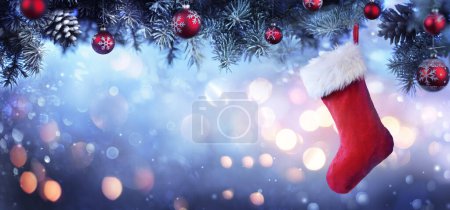 Foto de Medias colgando del árbol de Navidad - Calcetín rojo con luces de nieve y bokeh - Imagen libre de derechos