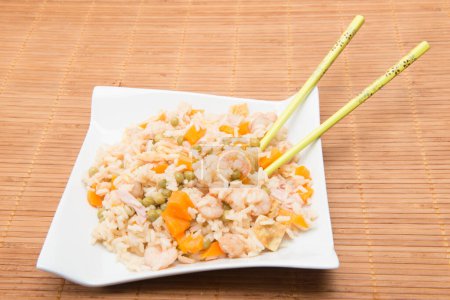 Téléchargez les photos : Plat de riz aux légumes avec baguettes sur nappe en bambou - en image libre de droit