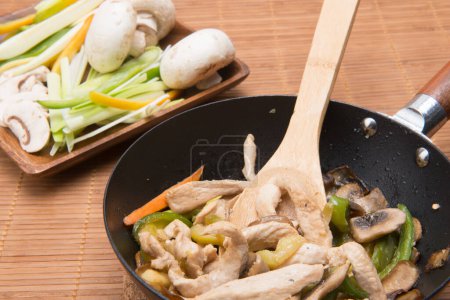 Photo for Mushroom wok with vegetables on a table with a bamboo tablecloth - Royalty Free Image