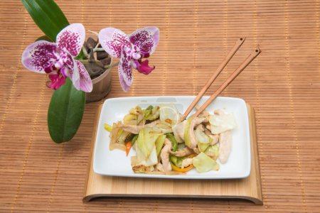 Foto de El plato fúngico con hortalizas sobre la mesa con el mantel de bambú y la orquídea - Imagen libre de derechos