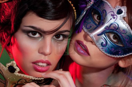 Foto de Pareja de mujeres sensuales con maquillaje colorido y máscaras de carnaval - Imagen libre de derechos