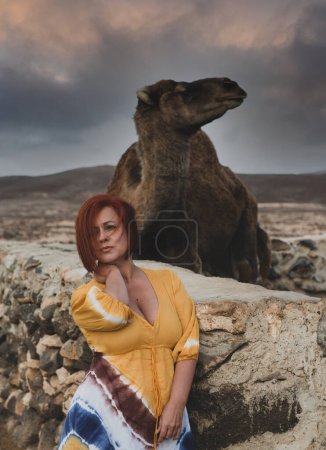 Foto de Woman in a desert landscape with camels - Imagen libre de derechos