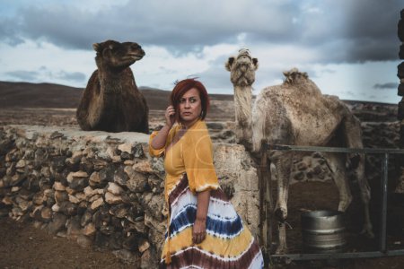 Téléchargez les photos : Woman in a desert landscape with camels - en image libre de droit