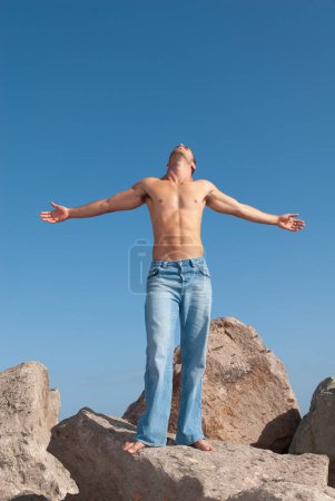 Photo for Strong man in jeans and no t-shirt under the blue sky in summer or spring - Royalty Free Image