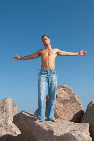 Photo for Strong man in jeans and no t-shirt under the blue sky in summer or spring - Royalty Free Image