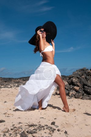 Foto de Attractive woman with hat in a coastal area and beach in good weather - Imagen libre de derechos