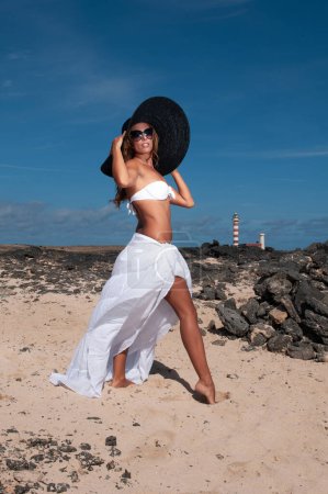Téléchargez les photos : Attractive woman with hat in a coastal area and beach in good weather - en image libre de droit