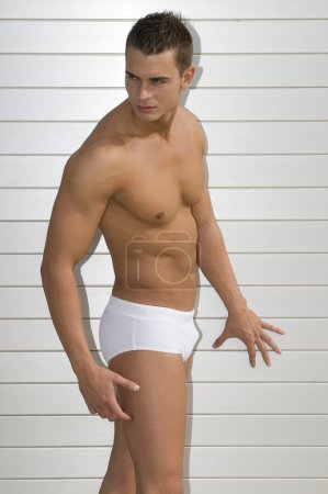 Foto de Attractive and muscular young man dressed. in a very short swimsuit - Imagen libre de derechos