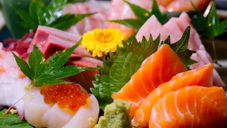 Foto de Primer plano de sashimi de pescado fresco en rodajas con caviar. Delicadeza de mariscos crudos en el restaurante japonés. Delicioso surtido de sashimi de hirame, maguro, tako. Cocina japonesa servida en un restaurante de alta cocina. - Imagen libre de derechos