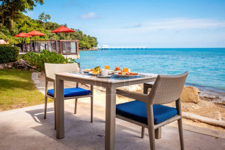 Photo for Breakfast table full of food at seaside restaurant, with sea view. Summer dinner at a beachfront restaurant in luxury hotel. Concept of travel, holidays, weekend, tropical vacation in resort. - Royalty Free Image