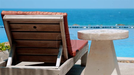 Téléchargez les photos : Chaise de plage au bord de la piscine par une journée ensoleillée. Concept de détente et vacances d'été. - en image libre de droit