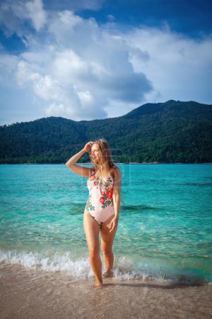 Téléchargez les photos : Femme en maillot de bain apprécie la beauté de la plage tropicale avec de l'eau turquoise. Voyage et vacances d'été concept. - en image libre de droit