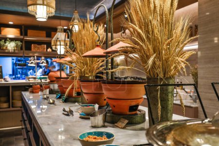 Téléchargez les photos : Buffet rustique avec casseroles en terre cuite et décoration de blé. Présentation culinaire. - en image libre de droit