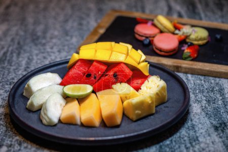 Téléchargez les photos : Fruits frais assortis soigneusement présentés sur une assiette sombre. Alimentation saine et mode de vie. - en image libre de droit