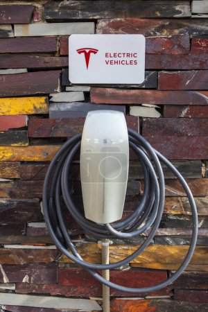 Photo for Alcantara, Spain - Oct 6th, 2022: Tesla Electric car charging station at rural enviroment. Natural rust slate wall. Alcantara Caceres, Spain. - Royalty Free Image