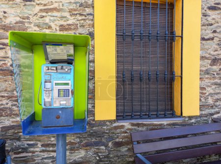 Foto de La Codosera, Badajoz - 19 / 08 / 2021: Cabina telefónica no cerrada instalada en el área rural. Paseo lateral con banco público - Imagen libre de derechos