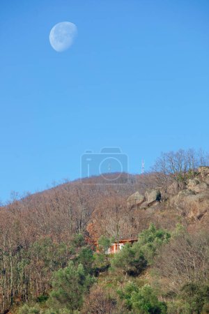 Foto de Casa de campo en la colina con luna grande encima. Banos de Montemayor, Otoño mágico del Valle de Ambroz, Extremadura, España - Imagen libre de derechos