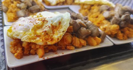Foto de Patatas revueltos con huevo frito y solomillo. Servido en el escritorio del bar de tapas - Imagen libre de derechos