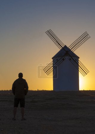 Foto de Man observing the Campo de Criptana windmills at rising through site, Spain. Ciudad Real, Spain - Imagen libre de derechos