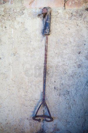 Foto de Branding iron for cattle hanging from a nail on the adobe wall of an old stable. Selective focus - Imagen libre de derechos