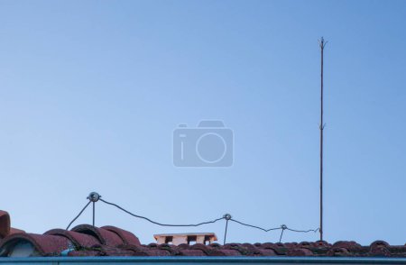 Photo for Traditional lighting rod over tile roof. Blue sky background - Royalty Free Image