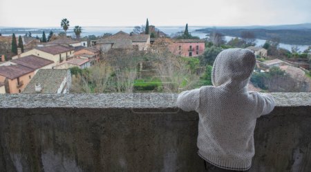 Photo for Granadilla village. Hooded child boy enjoying an aerial view from castle. Extremadura, Caceres, Spain - Royalty Free Image