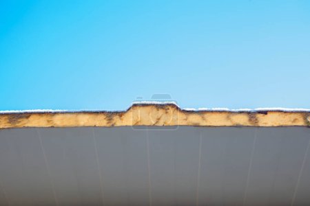 Photo for Roof insulated with sandwich panels and covered with winter frost. Blue sky background - Royalty Free Image