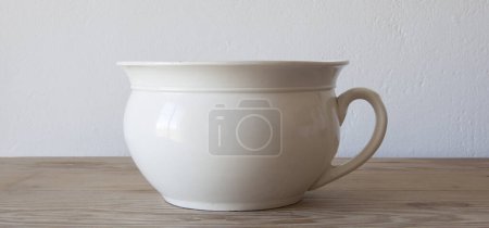 Photo for White porcelain camber pot over wooden surface. Selective focus - Royalty Free Image