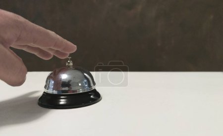 Foto de Invitado a punto de pulsar la campana de servicio en la recepción del hotel. Superficie blanca - Imagen libre de derechos