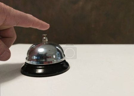 Foto de Invitado a punto de pulsar la campana de servicio en la recepción del hotel. Superficie blanca - Imagen libre de derechos