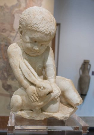 Photo for Cabra, Spain - May 19th, 2019: Child boy with hare. Archaeological Museum of Cabra Main Hall, Cordoba, Spain - Royalty Free Image