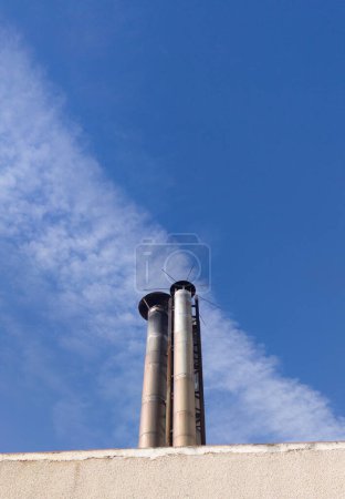 Téléchargez les photos : Cheminée industrielle protégée par un paratonnerre. Fond bleu ciel - en image libre de droit