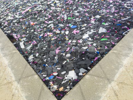 Téléchargez les photos : Revêtement de sol en particules de caoutchouc recyclé. Sol coussin noir avec particules multicolores - en image libre de droit