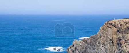 Photo for Visitor observing the sea from the top of cliff of Cabo Sardao coast, Ponta do Cavaleiro, Sao Teotonio, Portugal - Royalty Free Image