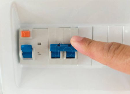 Photo for Finger pressing the lever of residual current operated circuit breaker. Selective focus - Royalty Free Image