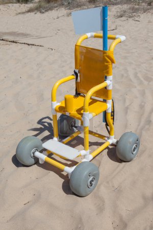 Foto de Silla de ruedas de playa para niños en arena lista para usar. Concepto de turismo accesible - Imagen libre de derechos