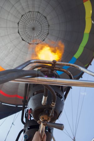 Photo for Hot air balloon pilot operating the burners. Low angle inside view - Royalty Free Image