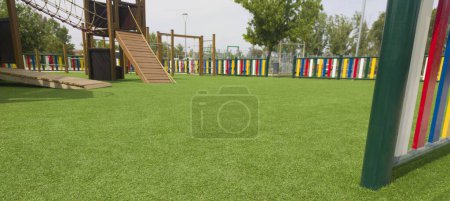 Photo for Artificial green grass floor on playground. Colourful rows of painted posts arround - Royalty Free Image
