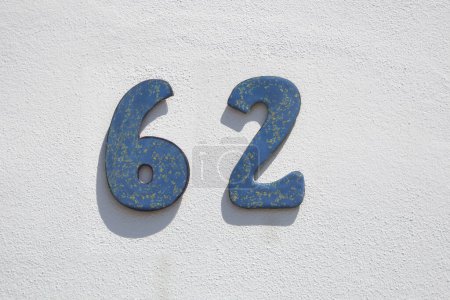 Haus Nummer 62. Angemaltes Eisen über weiß getünchter Wand. Häuser mit Persönlichkeitskonzept
