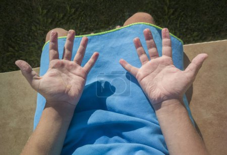 Téléchargez les photos : Enfant garçon montrant ses mains ridées après avoir nagé dans la piscine. Vue aérienne - en image libre de droit