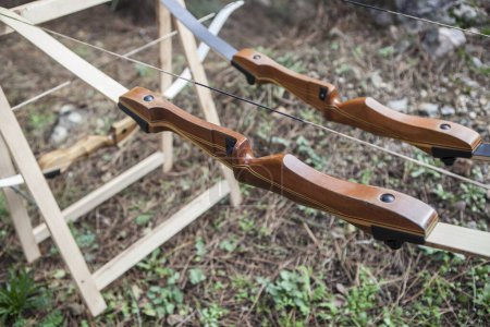 Téléchargez les photos : Arcs en bois affichés sur les sawhorses pliantes. Fond forestier - en image libre de droit