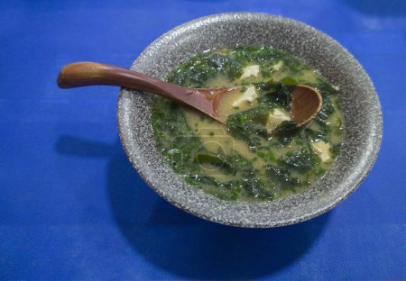 Foto de Sopa de miso con algas y tofu. Cuchara de madera en tazón gris - Imagen libre de derechos