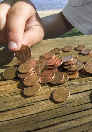 Foto de Niña contando sus ahorros de cambio de bolsillo. Mesa de picnic erosionada como fondo - Imagen libre de derechos