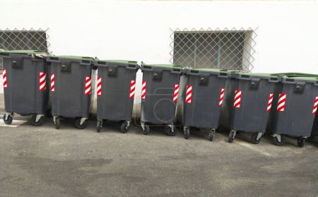 Foto de Línea de basureros grises frenando en pendiente. Fondo urbano - Imagen libre de derechos