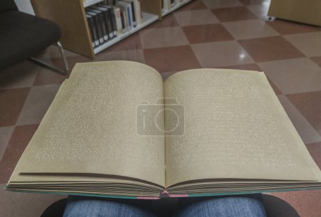Téléchargez les photos : Un homme aveugle lisant un livre en braille à la bibliothèque. Point de vue plan - en image libre de droit