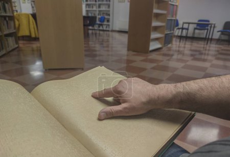 Téléchargez les photos : Un homme aveugle lisant un livre en braille à la bibliothèque. Point de vue plan - en image libre de droit