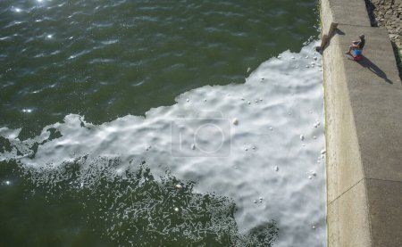 Foto de Hombre pescando en un río contaminado lleno de espuma. Peces capturados en aguas contaminadas - Imagen libre de derechos