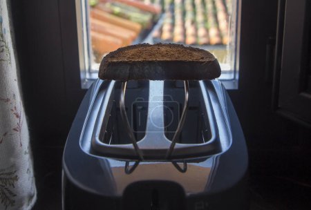 Toaster placed on the windowsill of a rural house. Fresh made slice over rack