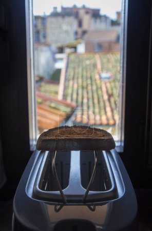 Toaster placed on the windowsill of a rural house. Fresh made slice over rack